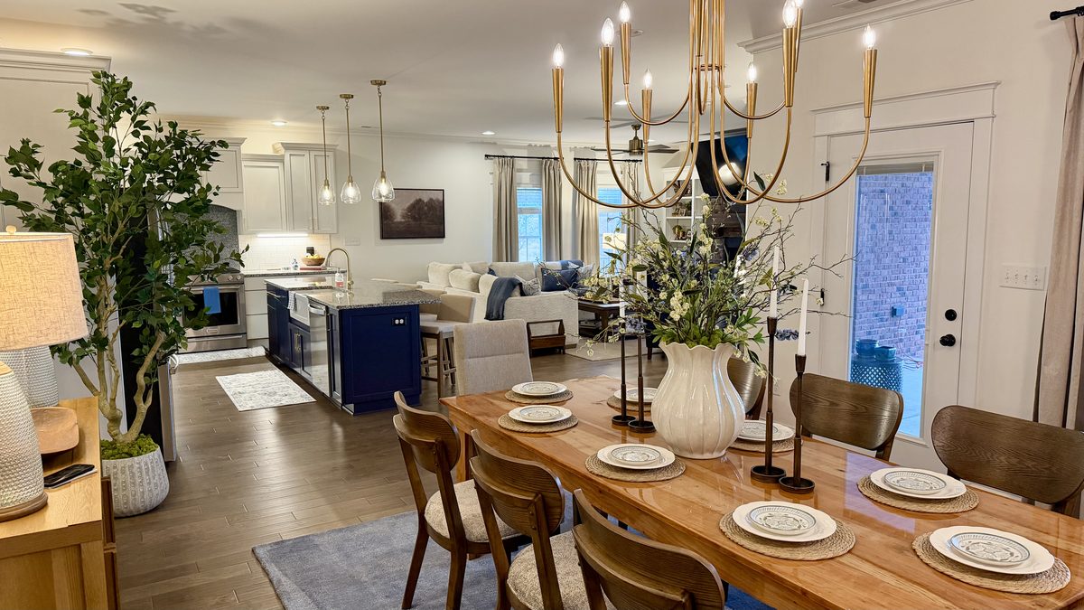 Open dining room with a brass chandelier, set table and view through to the kitchen